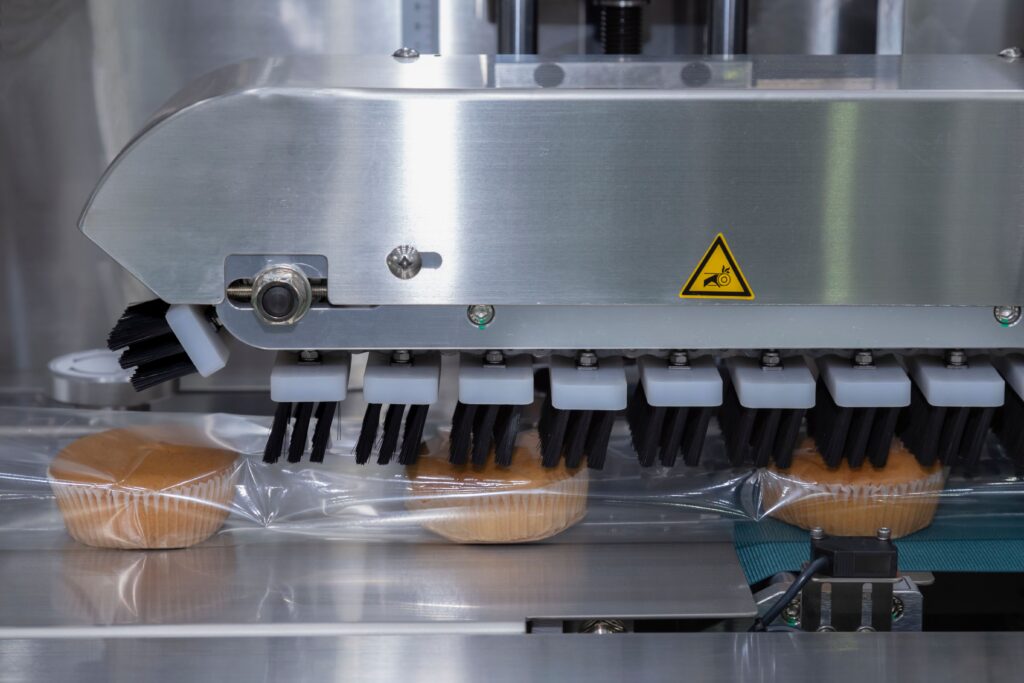 Food packaging conveyor belt wrapping muffins.