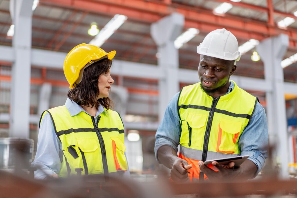 Two workers in a warehouse checking a conveyor belt.