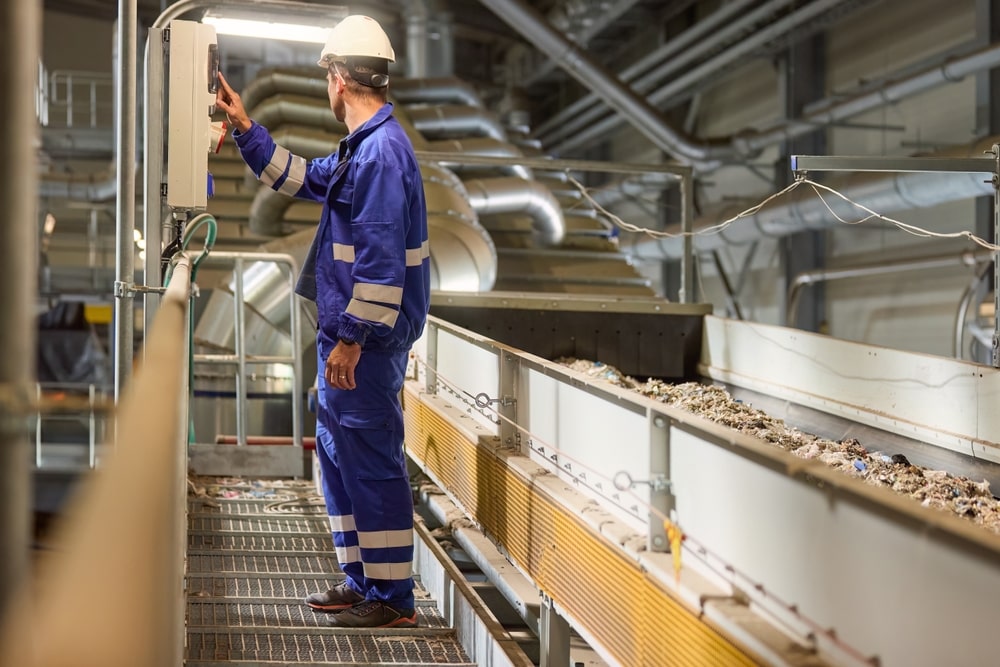 A worker watches conveyor belt tracking.