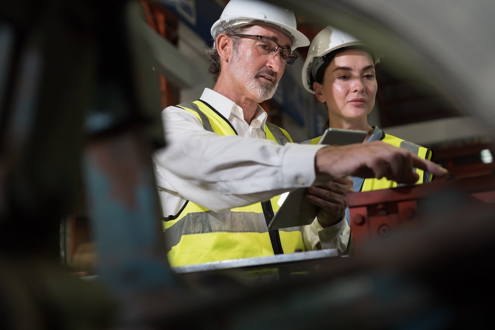 Two workers assess their conveyor belt's tracking.