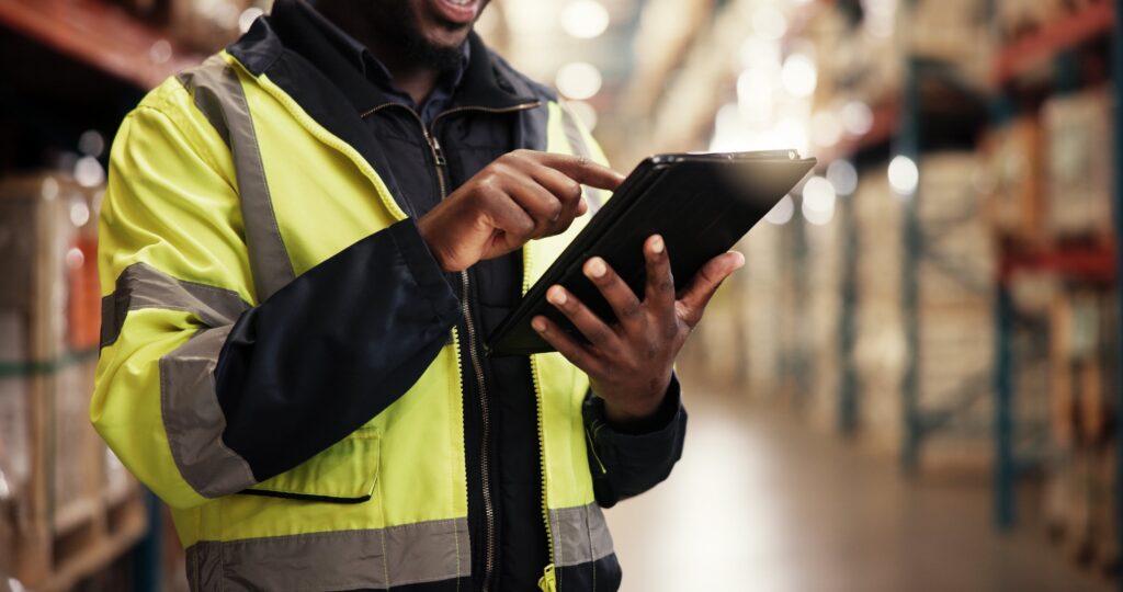 Worker taking inventory on his ipad in a warehouse.